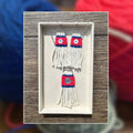 A pair of handmade woven earrings  and necklace, displayed on a wooden tray with a blurred background of colorful yarn balls.