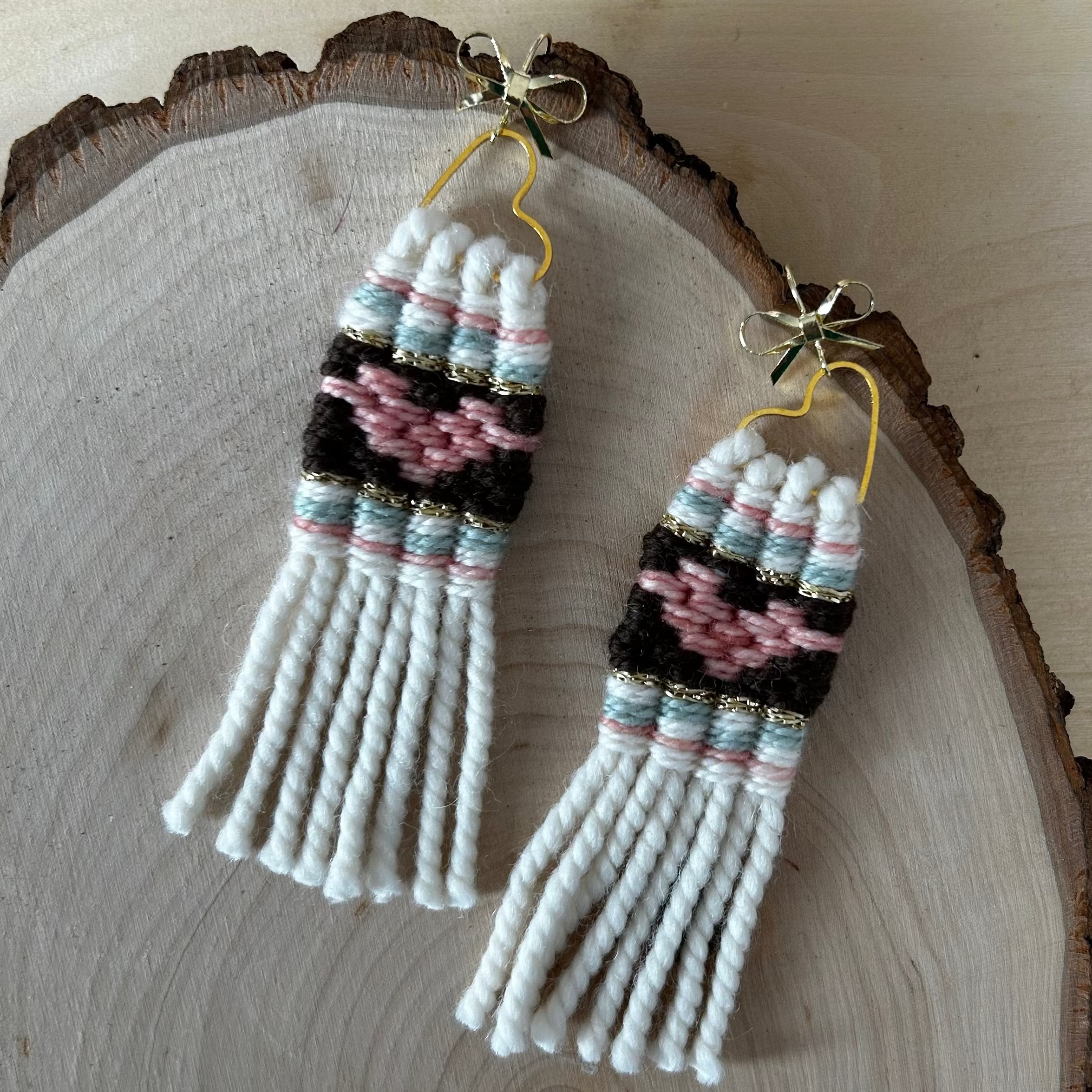 Pair of woven heart earrings on a wooden surface