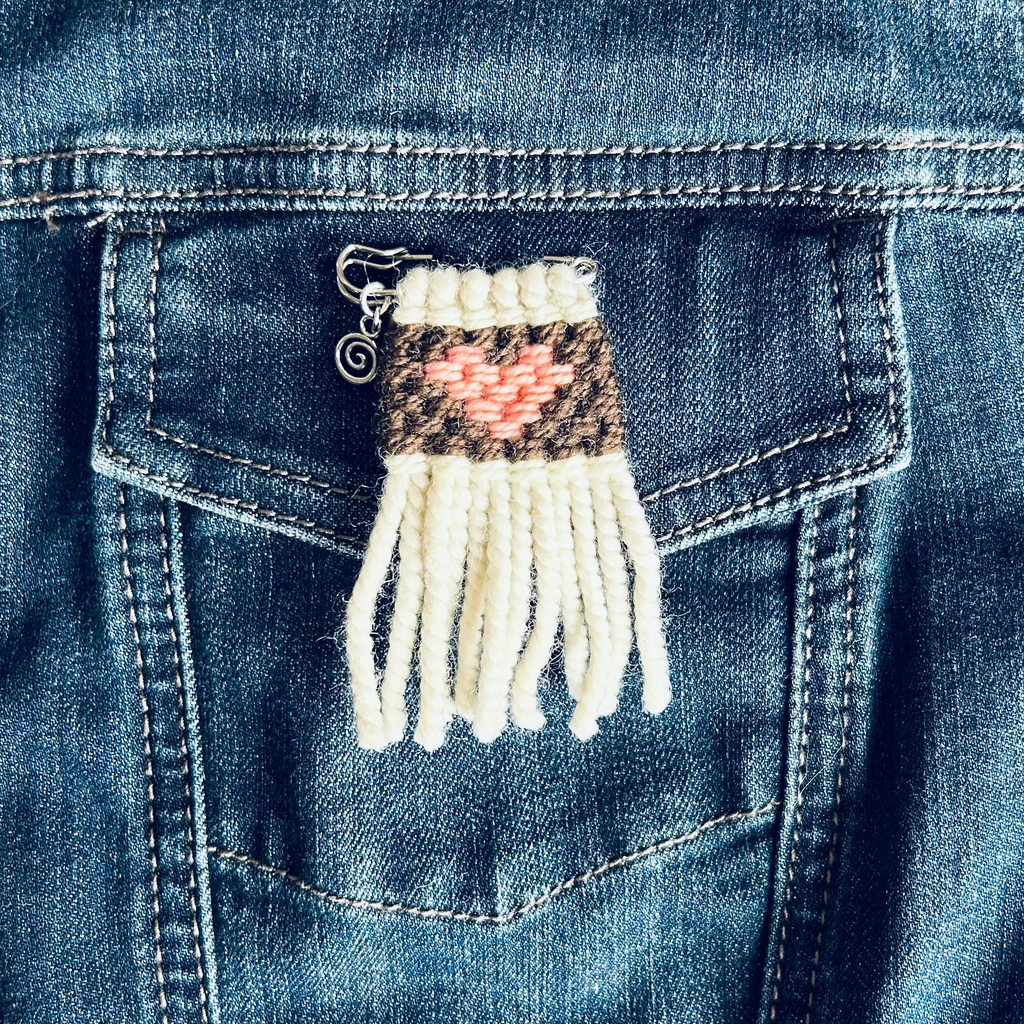 Woven heart pin on a blue denim jacket
