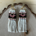 Pair of woven heart earrings on a wooden surface