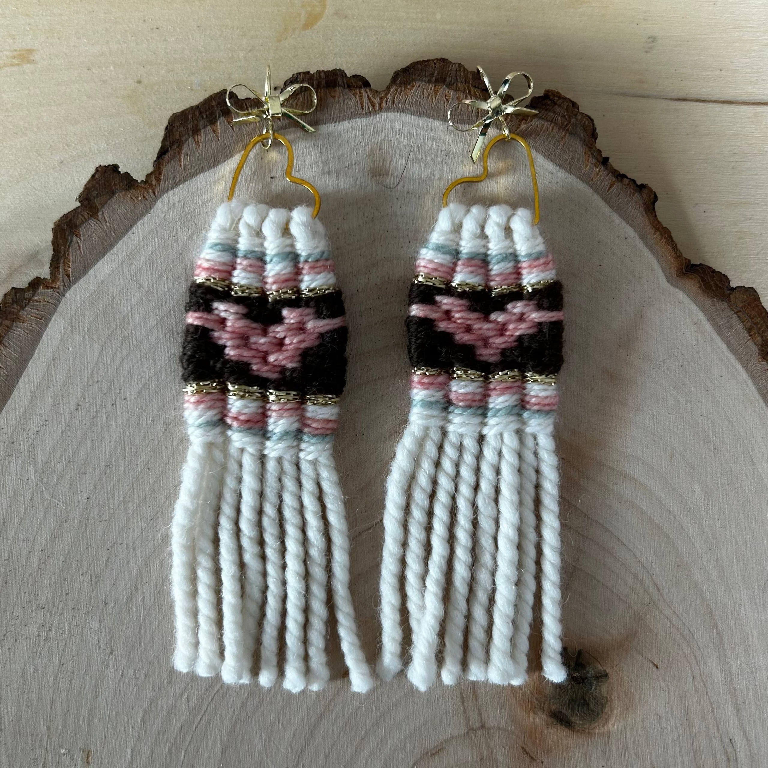 Pair of woven heart earrings on a wooden surface